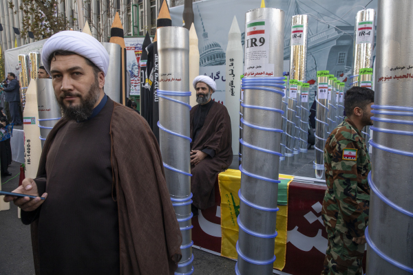 2025年11月4日：在伊朗德黑蘭舉行的集會上，兩名宗教人士出現在展示的離心機和伊朗導彈模型之間。