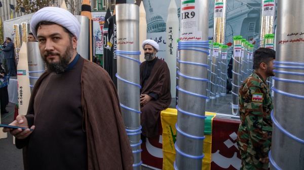 2025年11月4日:在伊朗德黑蘭舉行的集會上,兩名宗教人士出現在展示的離心機和伊朗導彈模型之間。