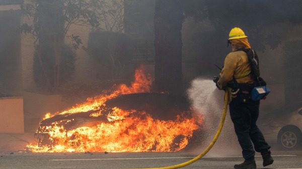 一名消防員正在向一輛燃燒的汽車噴水滅火。(圖片來源:Apu Gomes/Getty Images)