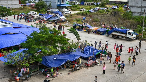 2025年12月14日,在柬埔寨班迭棉吉省的一个临时营地,流离失所的居民行走在柬埔寨与泰国边境冲突的阴影下。)