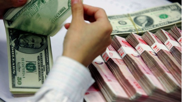 2005年7月22日，中国出局，在上海一家银行，一名银行出纳员在清点人民币和美元。随着亚洲加强合作，并希望使其长期与美元挂钩的巨额外汇储备多样化，中国谨慎的人民币重估将提高亚洲货币的价值。（图片来源： STR/AFP via Getty Images)