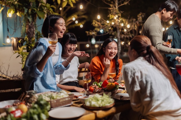 一群快乐的朋友聚在一起享用户外晚餐。(图片来源:Crystal/stock.adobe.com)