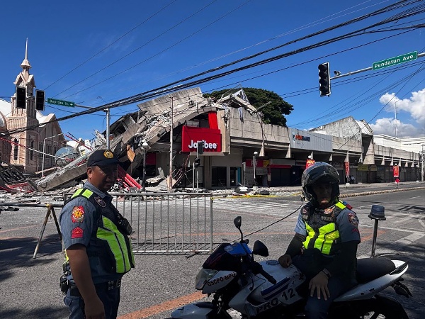 2026年6月8日，菲律賓桑托斯將軍市發生7.8級地震後，警察聚集在倒塌的Jollibee快餐店前。警方稱，6月8日襲擊菲律賓南部的7.8級地震造成至少一人死亡，多棟建築物倒塌，並引發了該地區的海嘯預警。（圖片來源：Edwin Espejo / AFP via Getty Images）