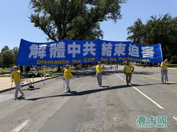 遊行隊伍的第二方陣「停止迫害法輪功」,法輪功學員舉著「解體中共 結束迫害」的橫幅