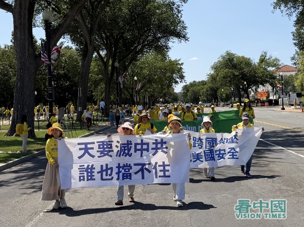 遊行隊伍的第三方陣,法輪功學員拉著「天要滅中共誰也檔不住」的橫幅