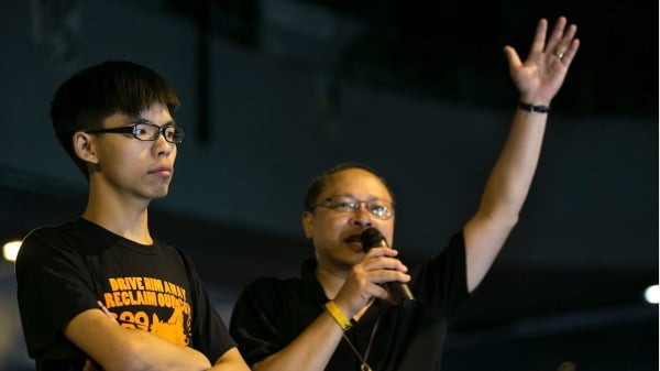 2014年10月19日，香港中央政府大樓外的民主抗議現場，學生領袖黃之鋒（左）聆聽「佔中」領袖戴耀廷在晚間會議上的講話。