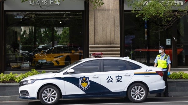 图为一位公安站在警车旁。（图片来源：Hugo Hu/Getty Images）