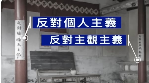 文章強調了廊柱上貼的兩個標語「反對個人主義，反對主觀主義」。（視頻截圖）