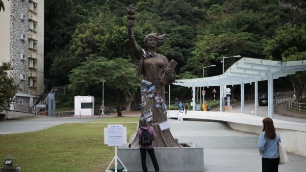 人们正在观看香港中文大学的“民主女神”雕像，雕像上覆盖着描绘2019年香港民主抗议最激烈时期校园围攻事件的照片。拍摄于2020年11月14日。（图片来源：DANIEL SUEN/AFP via Getty Images)