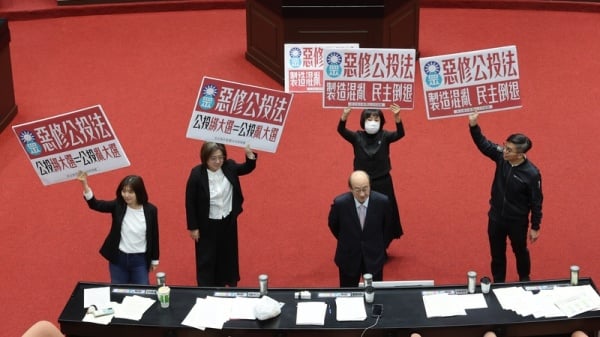 立法院會21日下午針對攸關公投綁大選的公投法第23條修正草案進行投票表決，民進黨立法院黨團在議場高舉標語表達反對立場。