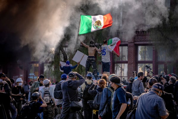2025年6月8日，洛杉磯發生反移民及海關執法局（ICE）騷亂。兩名示威者在一輛被毀的Waymo自動駕駛汽車上揮舞墨西哥國旗。