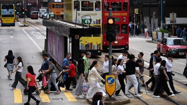 2025年7月15日，人们穿过香港西区的一条街道。（图片来源：PETER PARKS/AFP via Getty Images)