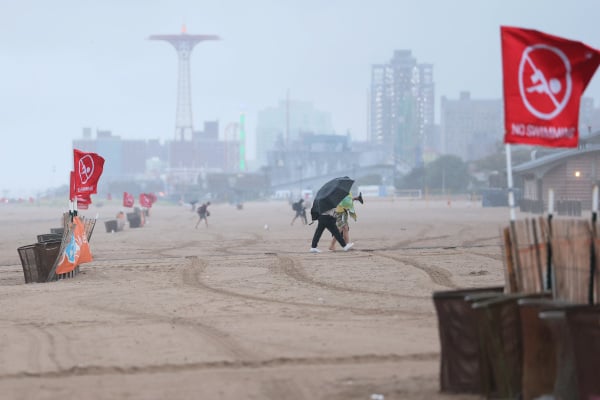 2025年8月20日，在纽约市布鲁克林区科尼岛附近的布莱顿海滩，人们看到“禁止游泳”的红色旗帜。