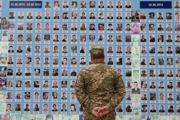 2025 年 8 月 24 日，烏克蘭獨立日，一名軍人在基輔的 「烏克蘭陣亡將士紀念牆 」前觀看陣亡戰友的照片，當時正值俄羅斯入侵烏克蘭。 