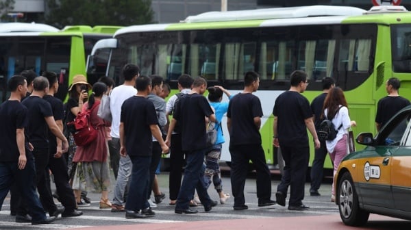2018年8月6日，P2P借贷平台受骗者到北京请愿，后在保全人员的护送下登上巴士离开。（图片来源：GREG BAKER/AFP via Getty Images）