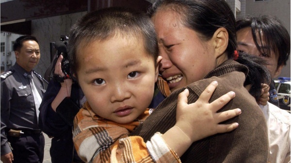 中国河南省郑州市一名妇女与丢失的儿子团聚时忍不住哭泣，儿子是从一群人贩子手中救出的。（图片来源：STR/Getty Images）