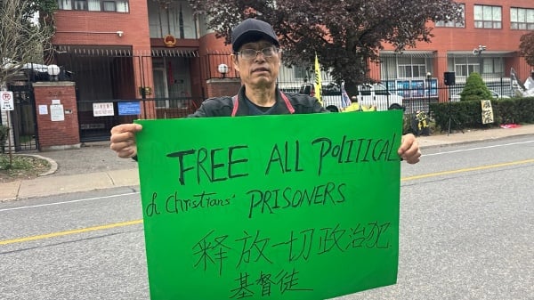 2026年10月1日，陈伟强参加在中领馆前的国殇日集会。他手持“释放所有政治犯”的展板。（看中国摄）