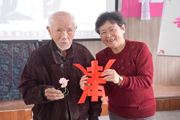 台湾花莲明义国小传统艺术詹淑美老师在社区关怀站重阳节活动中，致赠90岁以上的长者“寿”字剪纸和中国结作品。