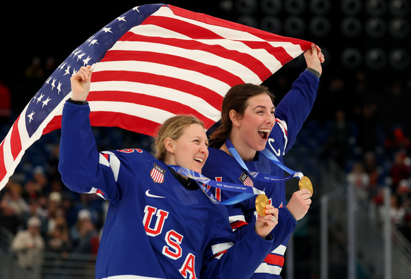 2026年2月19日：在米兰圣塔朱利亚冰球馆举行的2026年米兰-科尔蒂纳冬奥会女子冰球决赛（美国队对阵加拿大队）结束后，美国队获得金牌。图为美国队队员肯德尔·科因（26号）和希拉里·奈特（21号）在颁奖仪式后庆祝胜利。