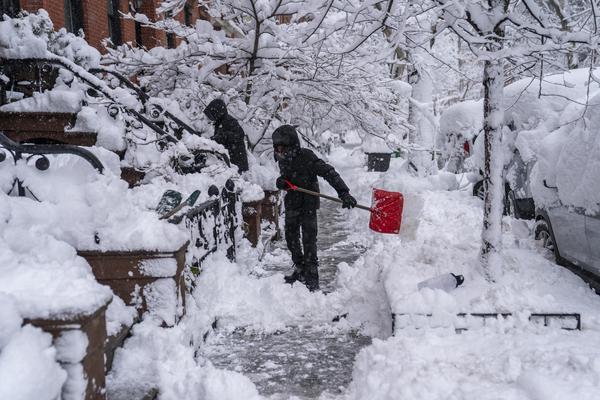 2026年2月23日：两名男子在纽约市布鲁克林区铲雪，积雪覆盖街道，能见度极低。美国东北部遭遇了东北风暴，带来暴雪、大雪和强风。（图片来源：Robert Nickelsberg/Getty Images）