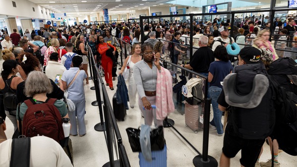 Travelers wait in line at a security checkpoint at Luis Munoz Marin International Airport i