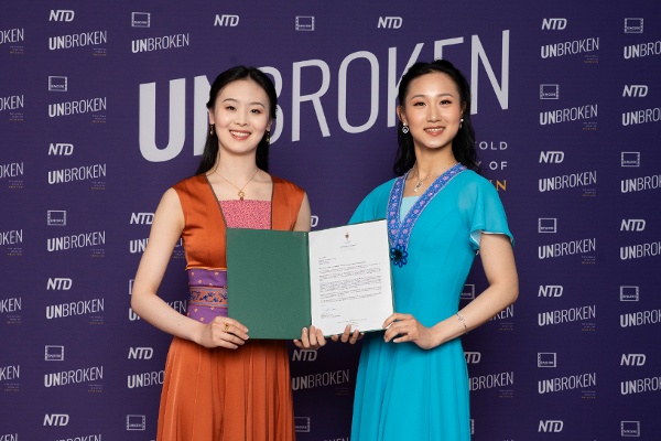 2026年4月22日晚，記錄片《堅不可摧：神韻幕後的故事》在多倫多舉行加拿大首映式，圖為首映式前的紅毯上，神韻藝術家Sunni Zhou（左）和Yingmei Zheng（右）手持加拿大政要頒發的賀信。（看中國特約攝影Evan）