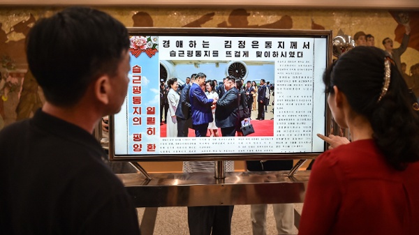 2026年6月9日，在平壤地鐵凱旋站，人們正在觀看螢幕上顯示的《勞動新聞》，該報刊登了中國國家主席習近平訪問北韓的新聞。（KIM Won Jin / AFP via Getty Images)