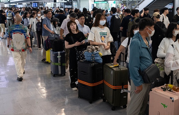 2026年8月14日，日本千叶县成田市，成田国际机场多条铁路线路因暴雨关闭后，旅客排队进入火车站。