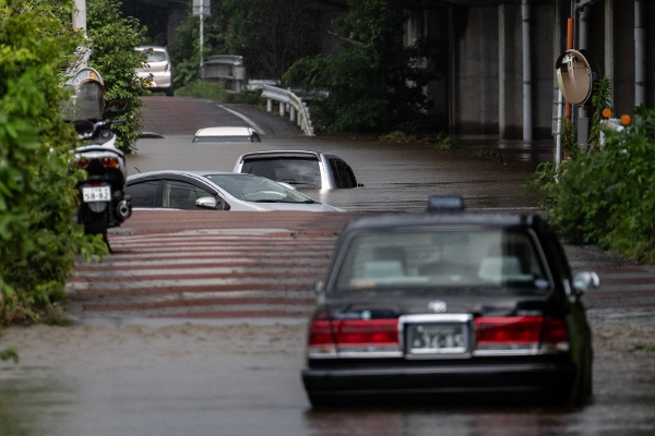 2026年8月14日，日本千叶县佐仓市，一条被洪水淹没的道路上，多辆被遗弃的汽车部分浸在水中。